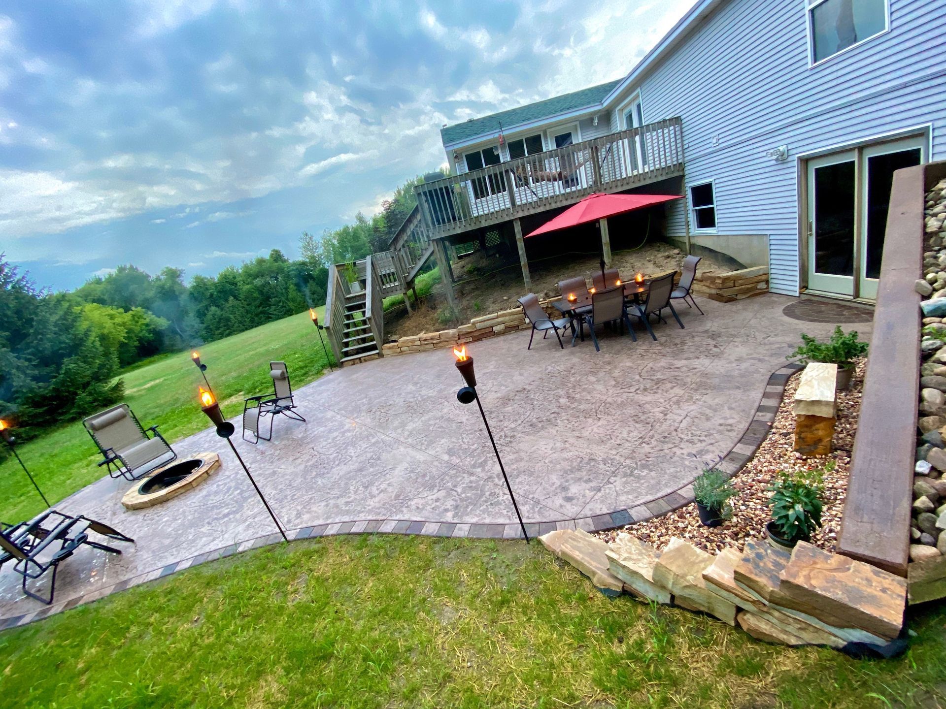 A large patio with a fire pit and a table and chairs in front of a house.