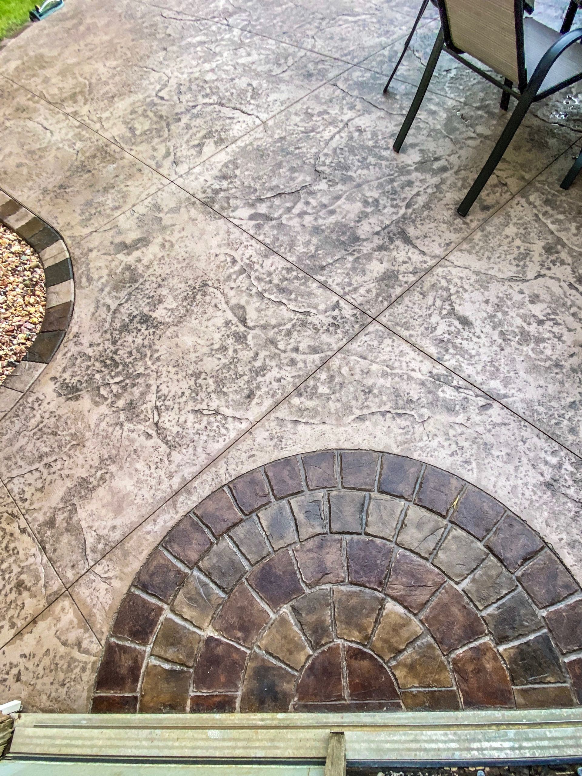 A patio with a circular design on the floor and chairs.