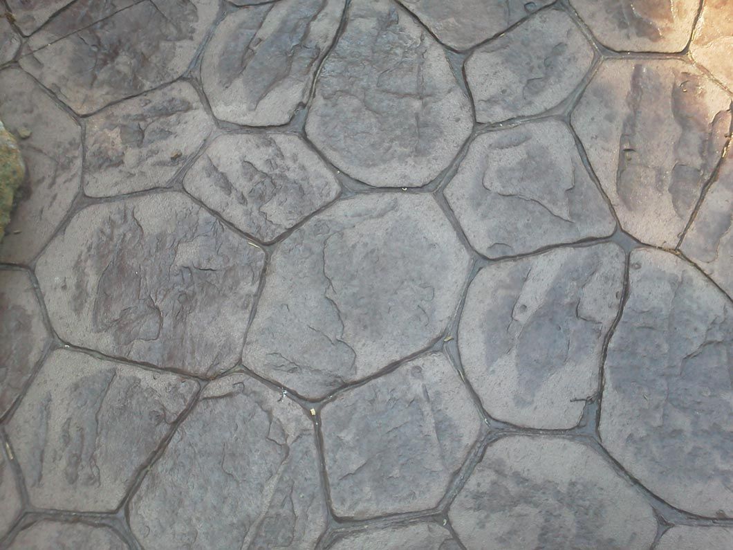 A close up of a concrete walkway with a stone pattern.