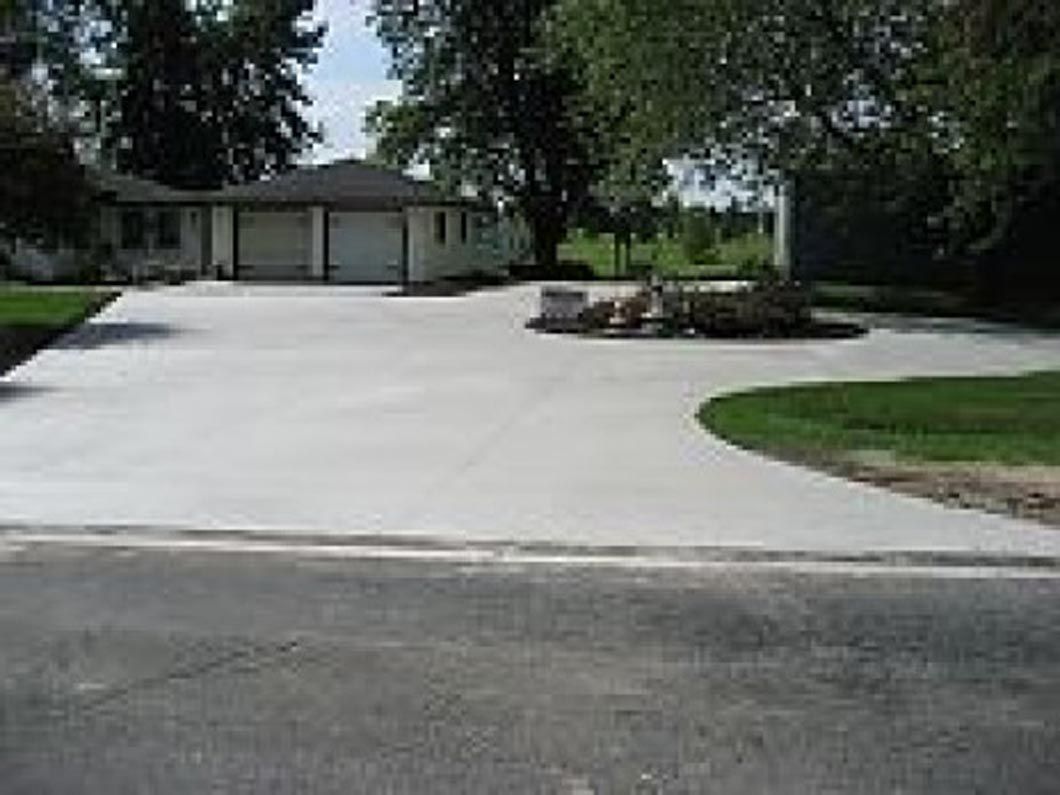 A concrete driveway leading to a house with a garage.
