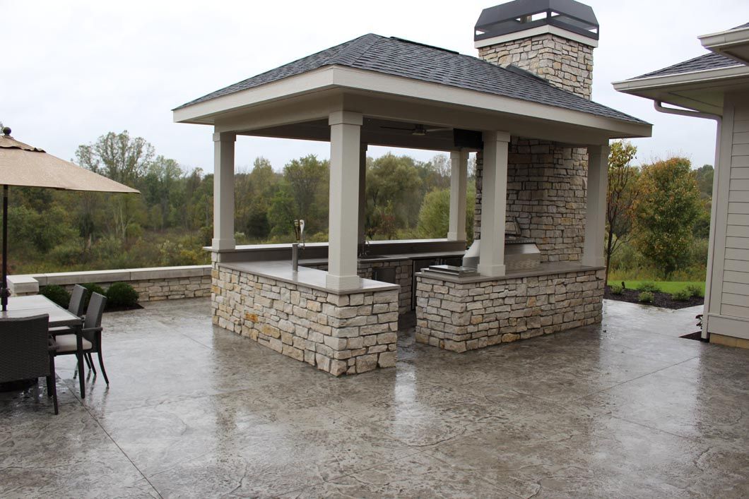 A patio with a gazebo and umbrellas on a rainy day.