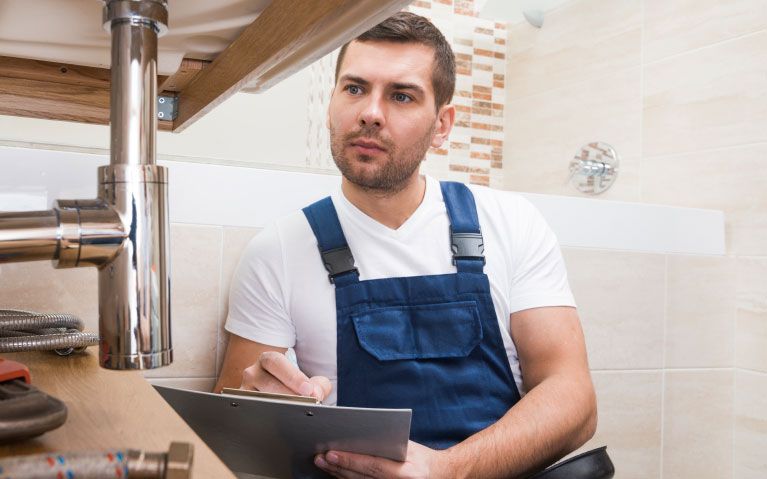 Young plumber fixing a sink in bathroom 

