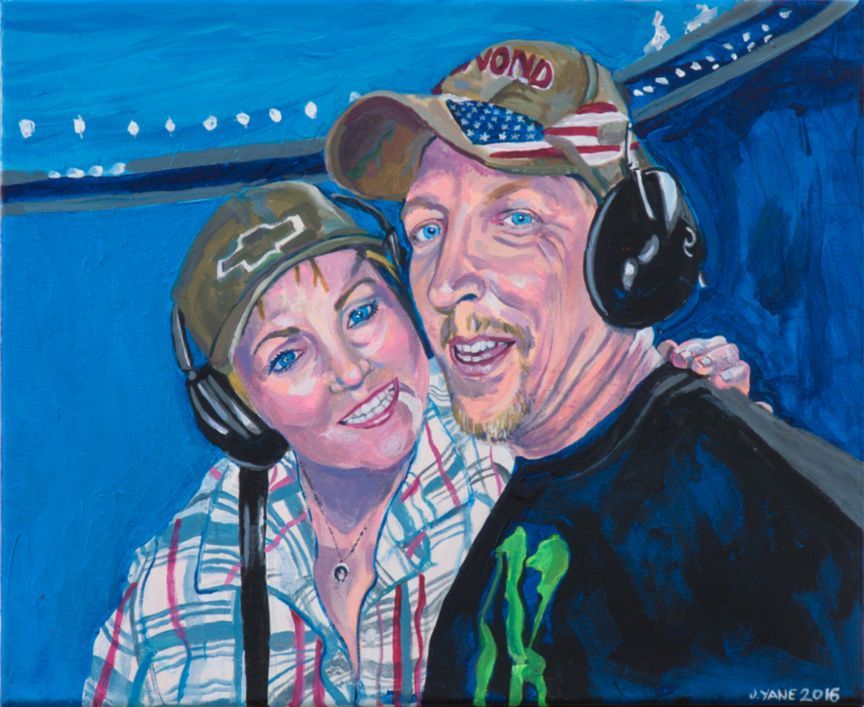 Couple smiling, wearing hats and headphones, against a blue background, possibly at an event.