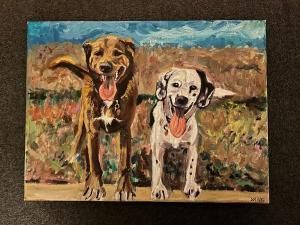 Two dogs panting happily, one brown, one dalmatian, standing in a field.