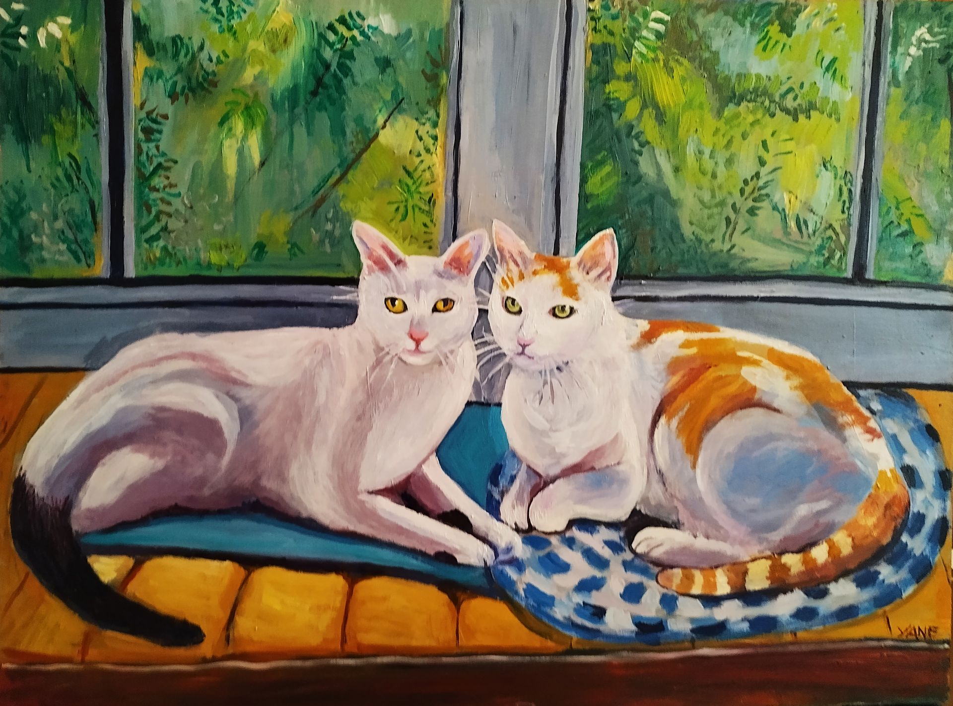 Two cats, white and orange, resting on a blue cushion by a window, looking at the viewer.