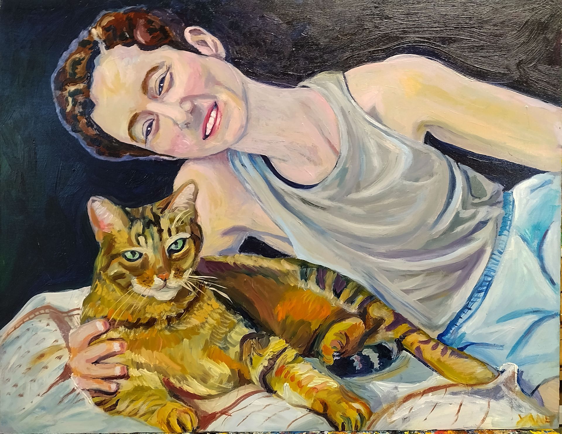 A person smiles, cuddling a tabby cat on a bed. The cat is orange and brown.