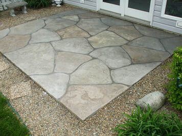 A patio with a lot of rocks on it and a bench in the background.