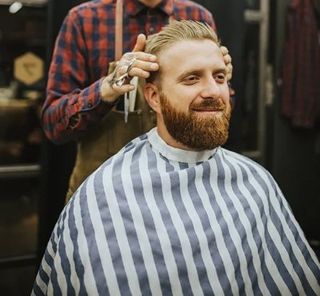 Good looking man visiting barber shop. Trendy and stylish beard styling and cut.