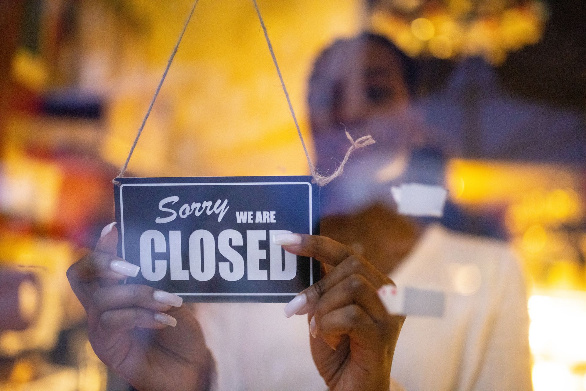 A woman is holding a sign that says Sorry, we are closed.