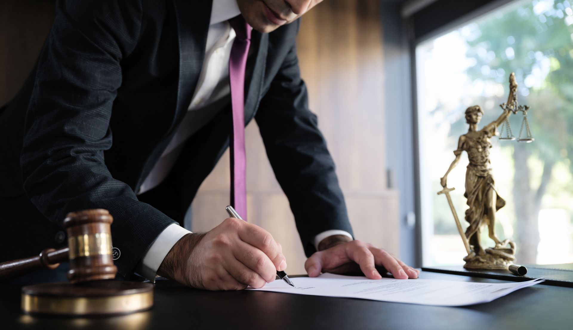 Wills and trust law lawyers preparing estate documents beside gavel and justice scale statue.