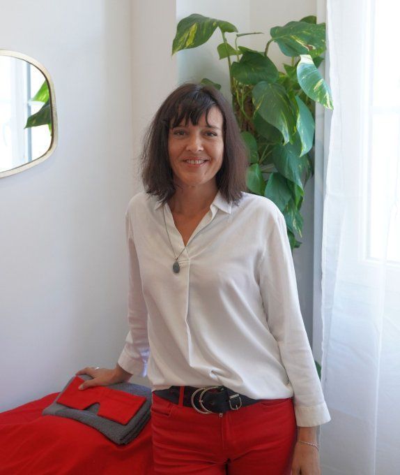 Une femme vêtue d'une chemise blanche et d'un pantalon rouge se tient devant un miroir