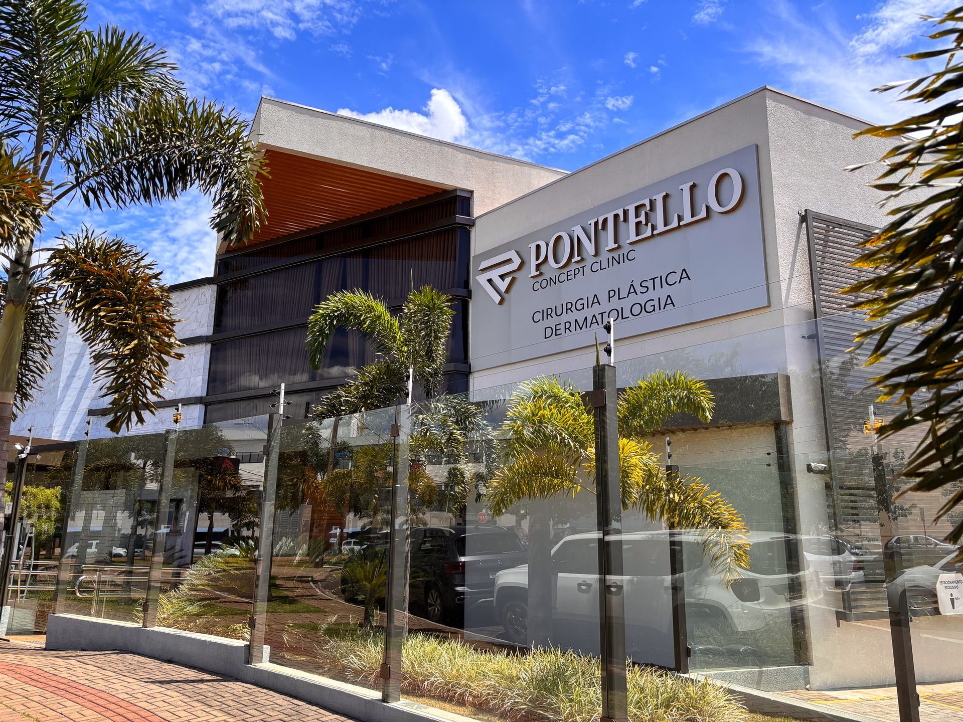 Um grande edifício com uma placa que diz pontello é cercado por árvores e uma cerca.