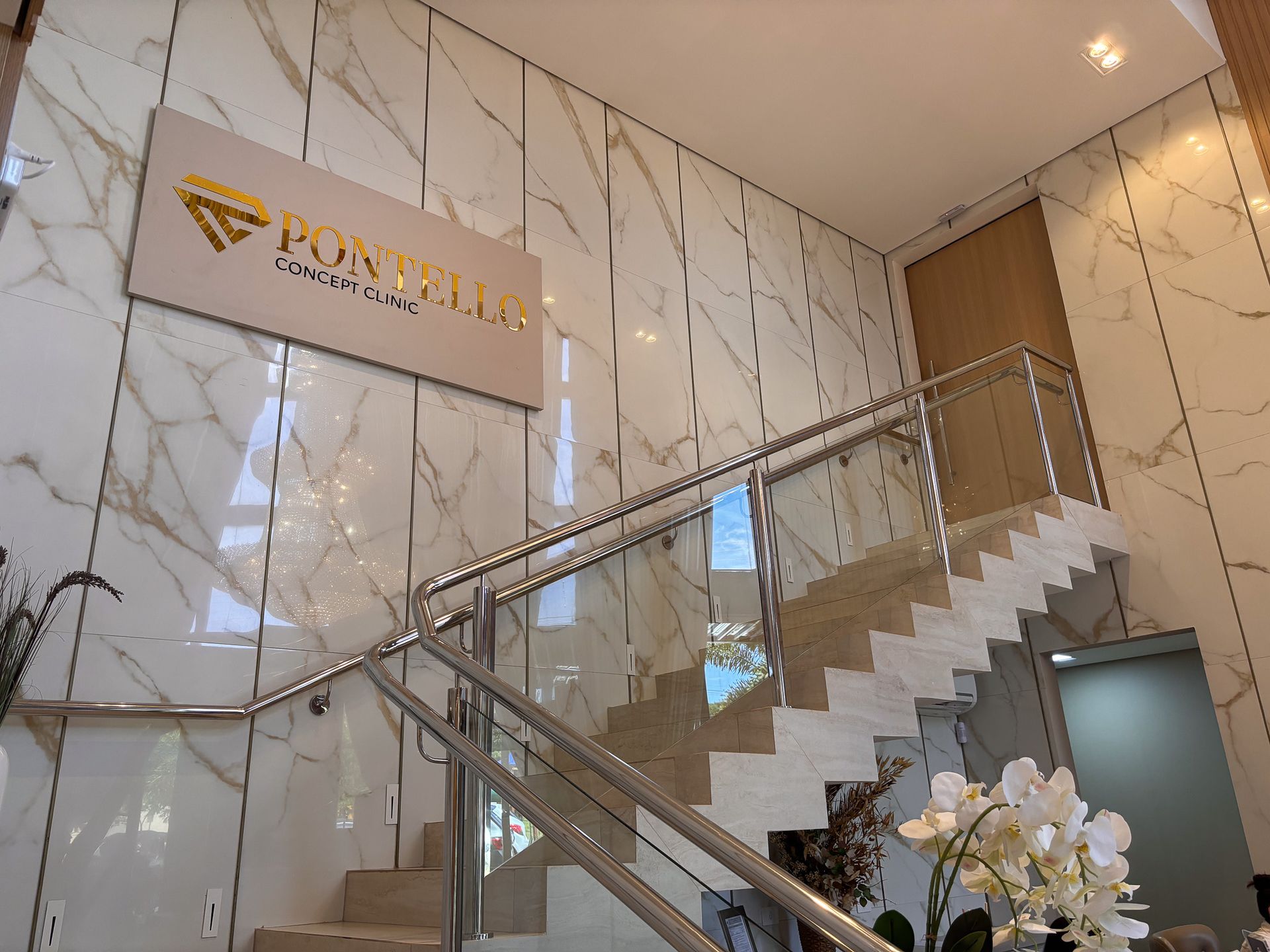 Uma escada com corrimão de vidro e uma placa na parede.