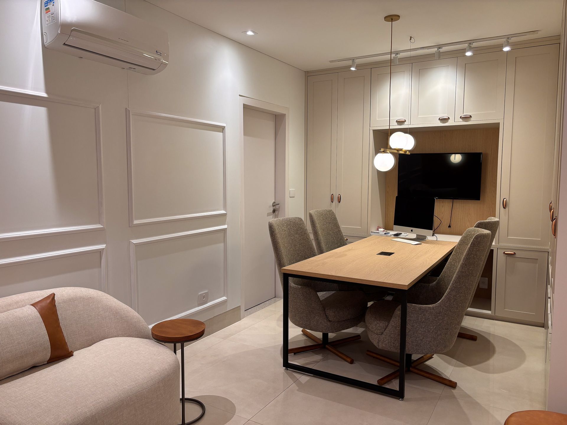 Uma sala de estar com mesa, cadeiras e televisão.