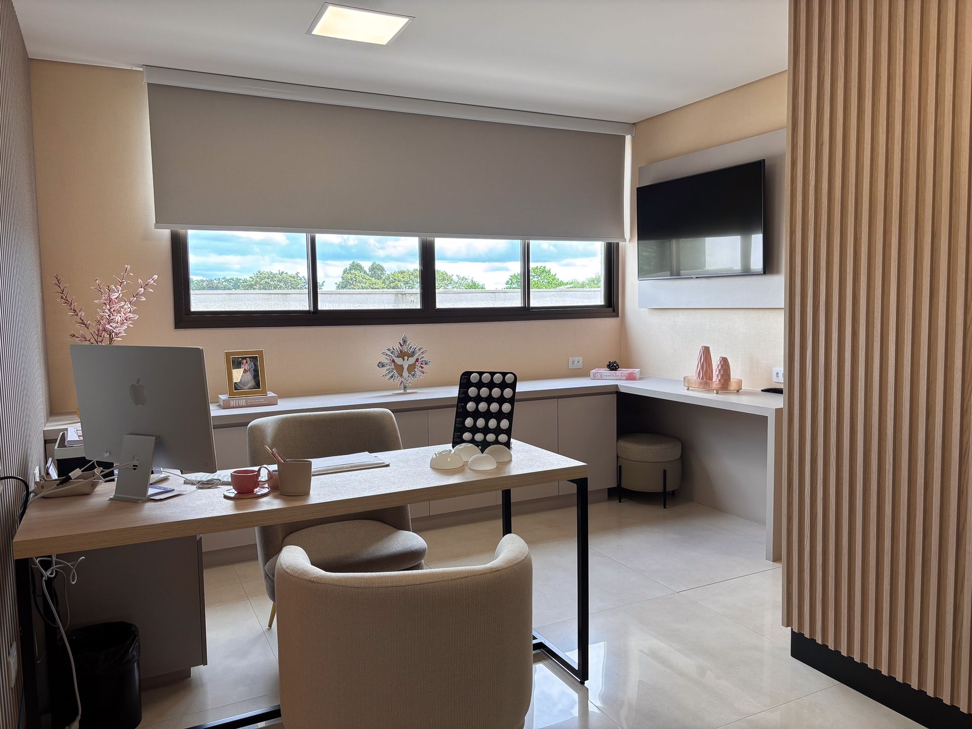 Uma sala com uma mesa, cadeira, computador e televisão.