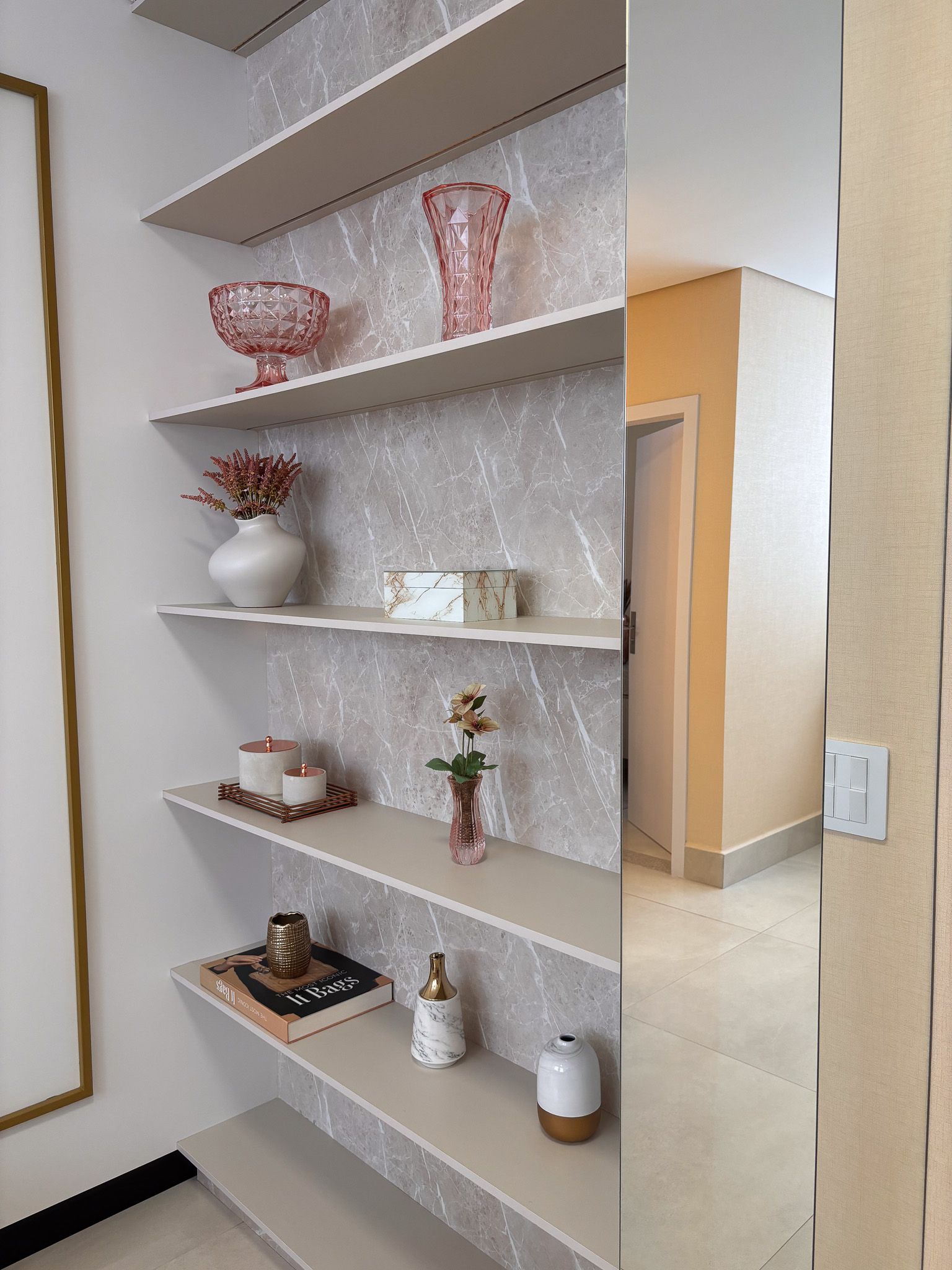 Uma sala com um espelho e prateleiras com vasos.