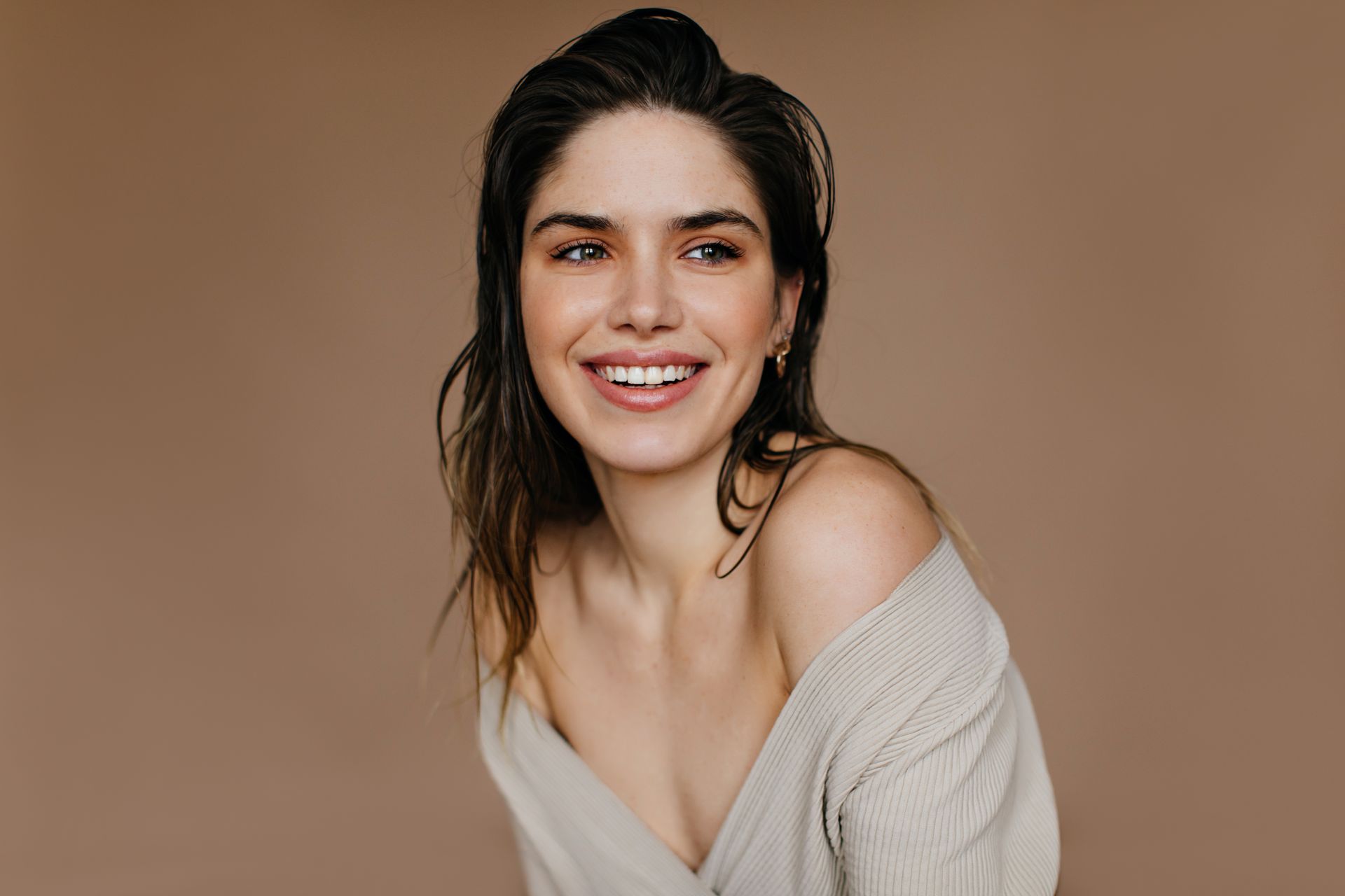 Uma mulher de suéter está sorrindo e olhando para a câmera.