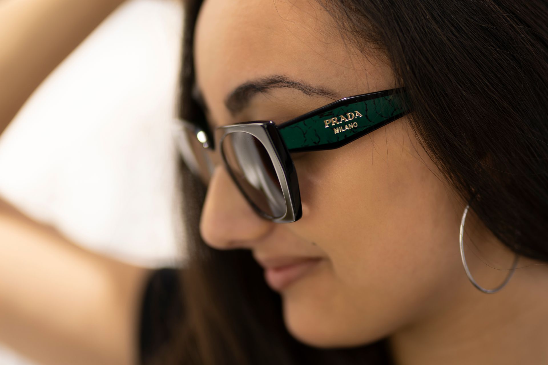 Primo piano di una donna che indossa occhiali da sole e orecchini a cerchio.