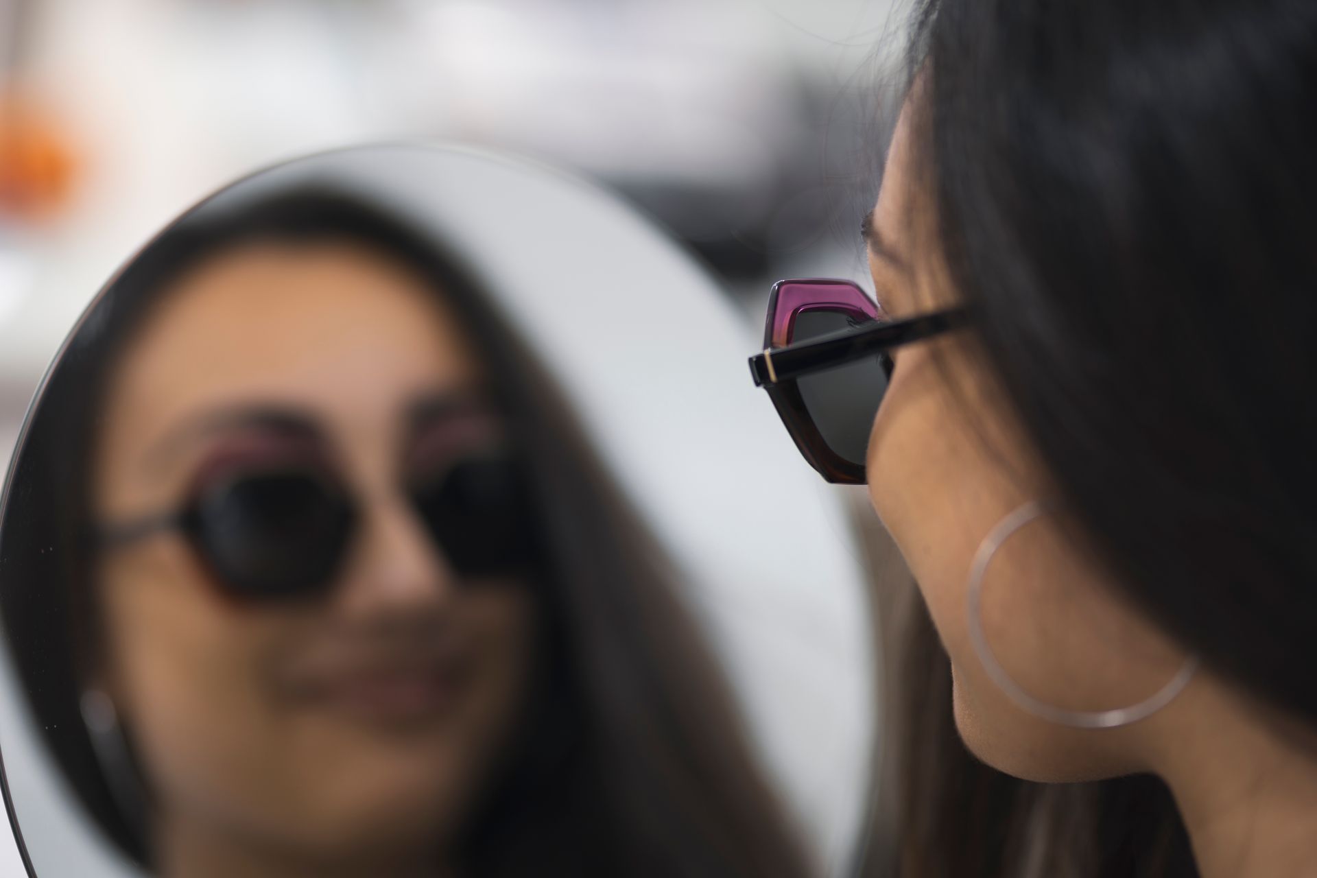 Una donna che indossa occhiali da sole si guarda riflessa in uno specchio.