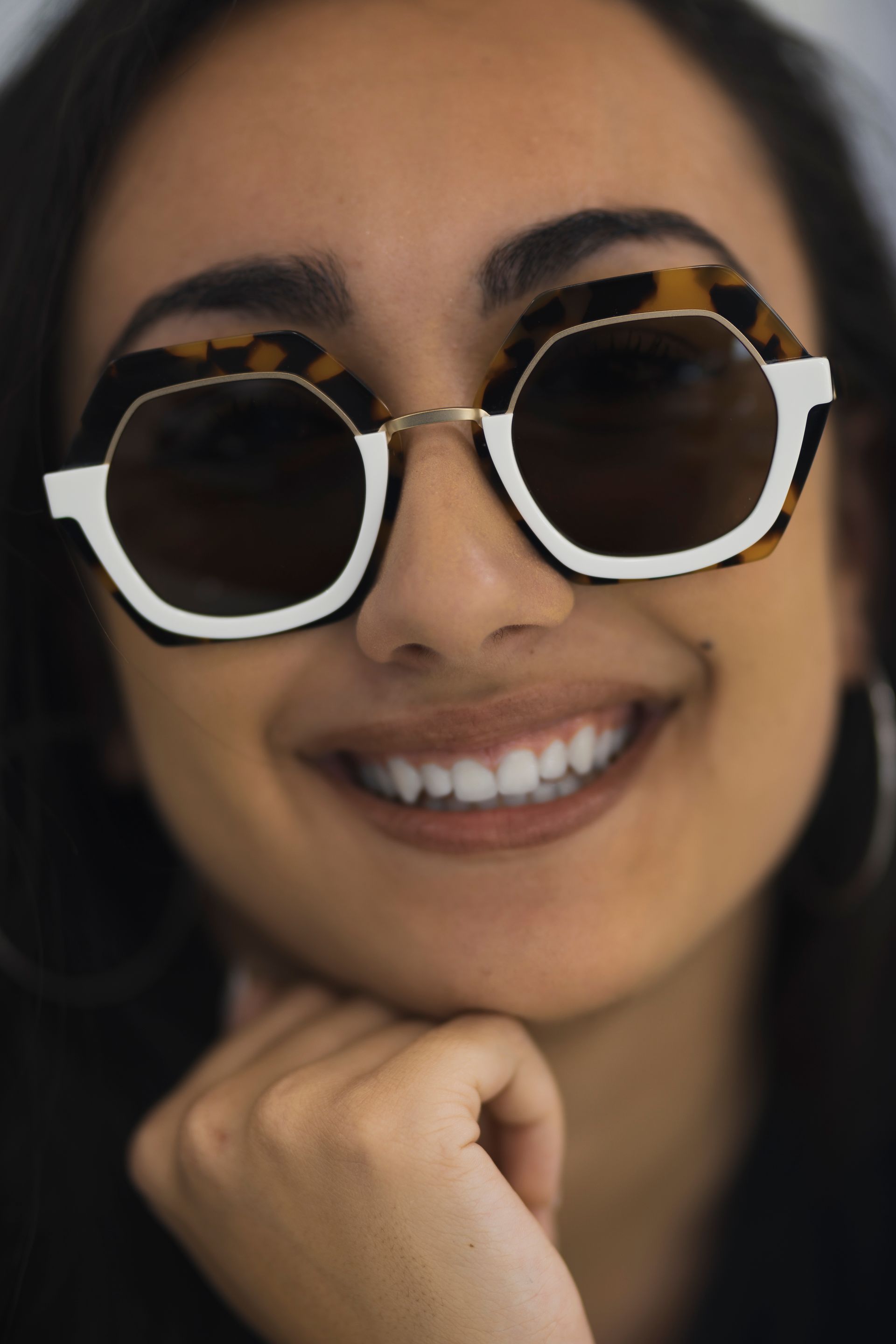 Un primo piano di una donna che indossa occhiali da sole e sorride