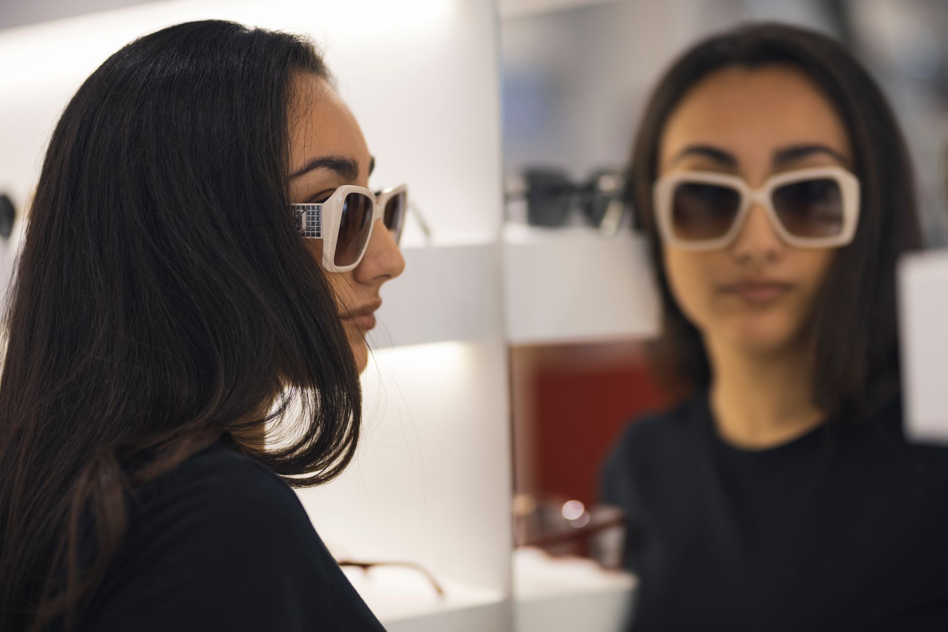 Una donna che indossa occhiali da sole si guarda riflessa in uno specchio