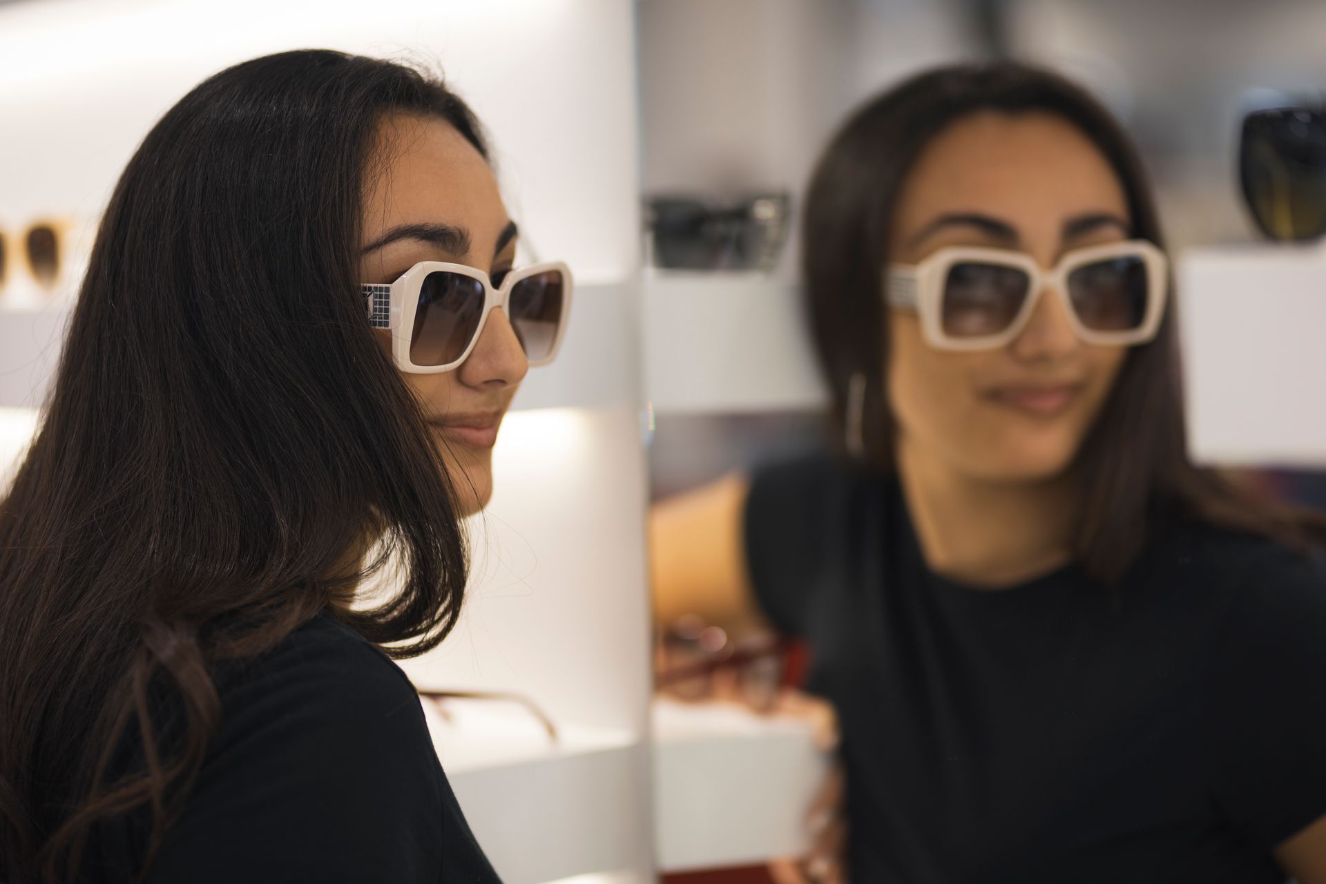 Una donna che indossa occhiali da sole si guarda riflessa in uno specchio.