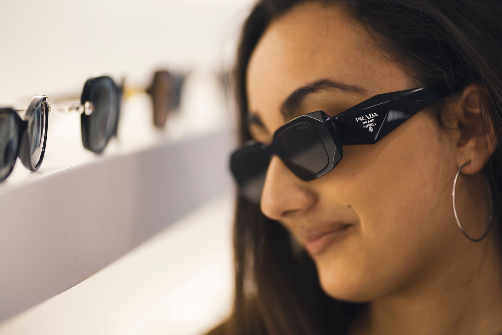 Una donna che indossa occhiali da sole sta osservando gli occhiali da sole su uno scaffale.