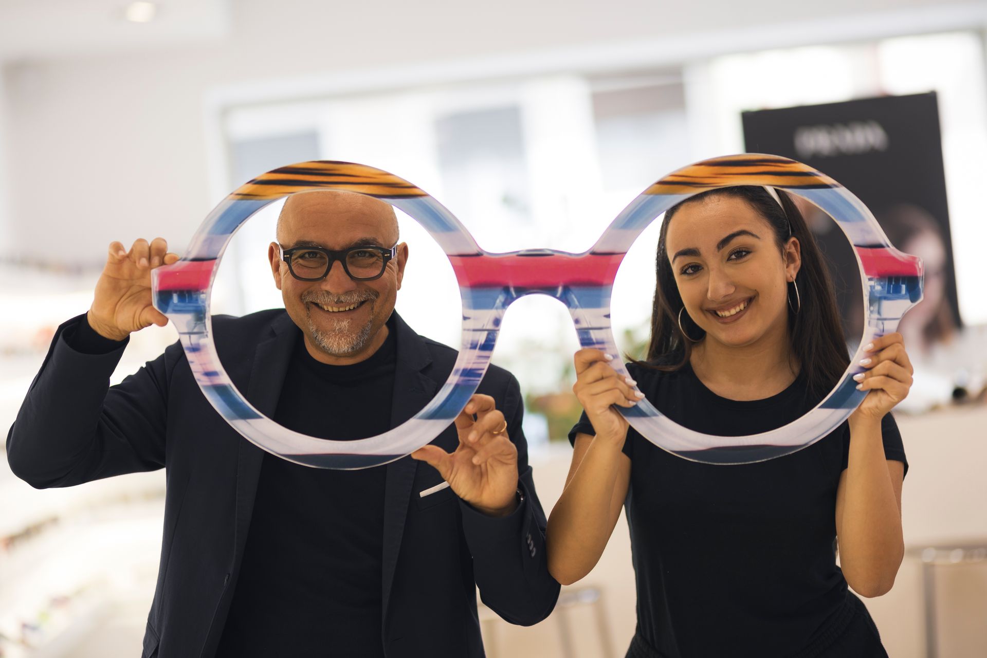 Un uomo e una donna tengono un paio di occhiali davanti al viso.