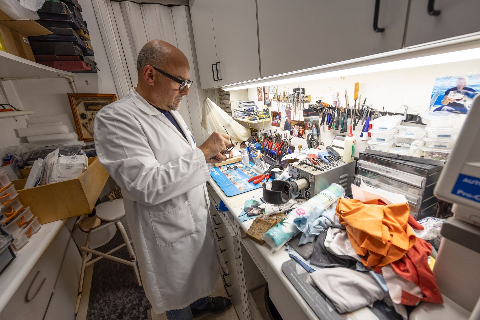 Un uomo in camice lavora in una stanza disordinata.