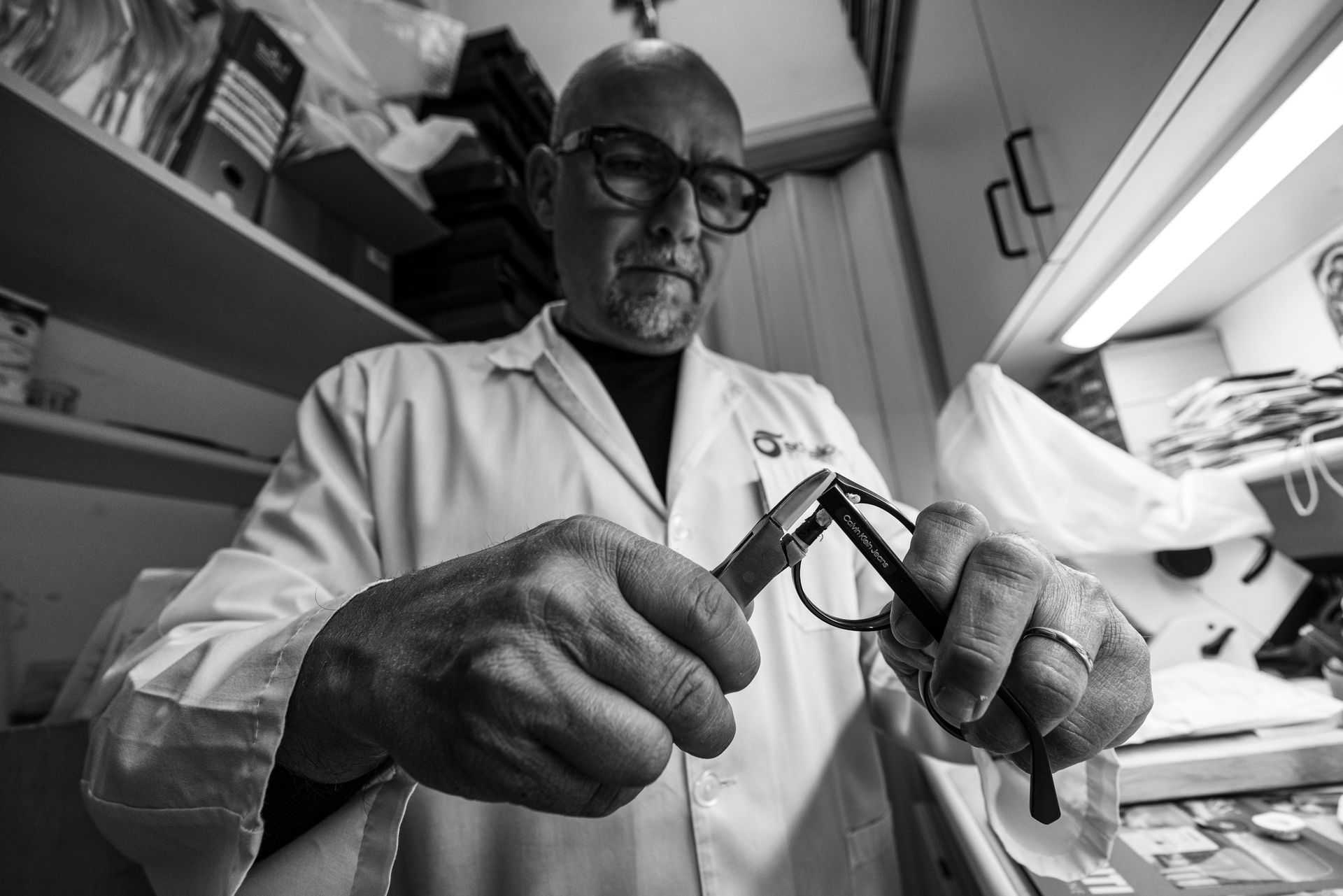 Un uomo in camice da laboratorio sta lavorando su un paio di occhiali.