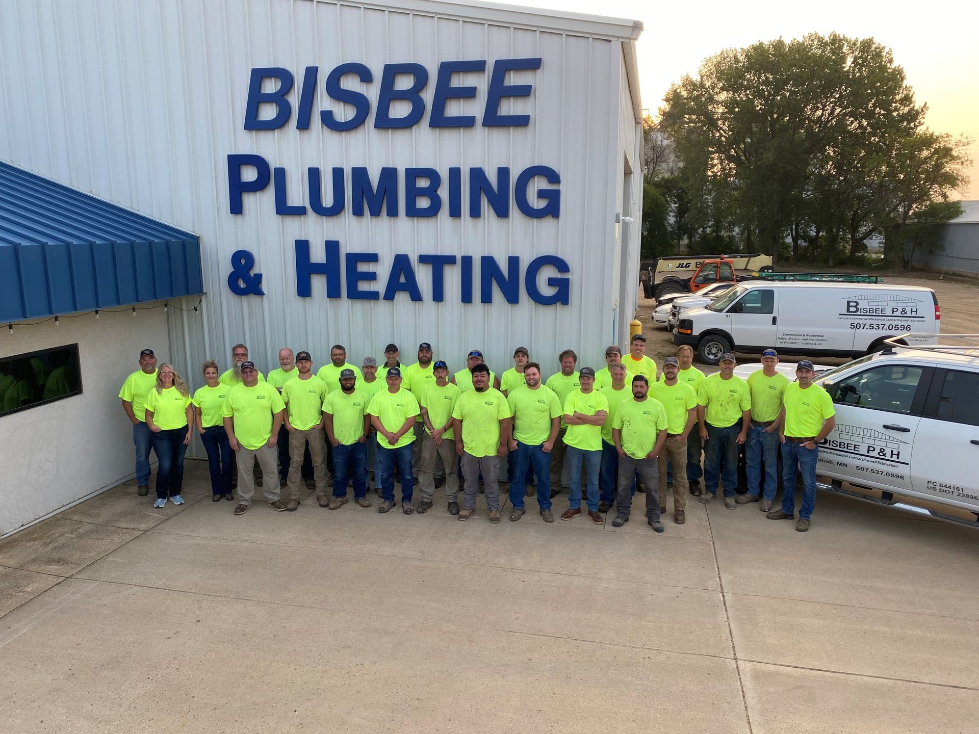 Group of employees in neon shirts pose in front of 