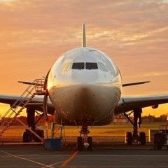 Airplane on the tarmac at sunset, with a maintenance ladder attached.