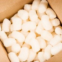 Cardboard box filled with white packing peanuts for cushioning.