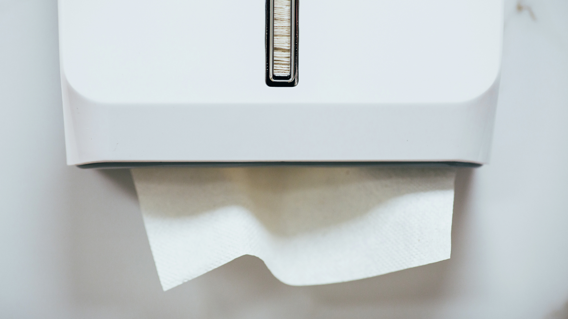 Public restroom with beige tiles, a sink, mirror, and a brown door.