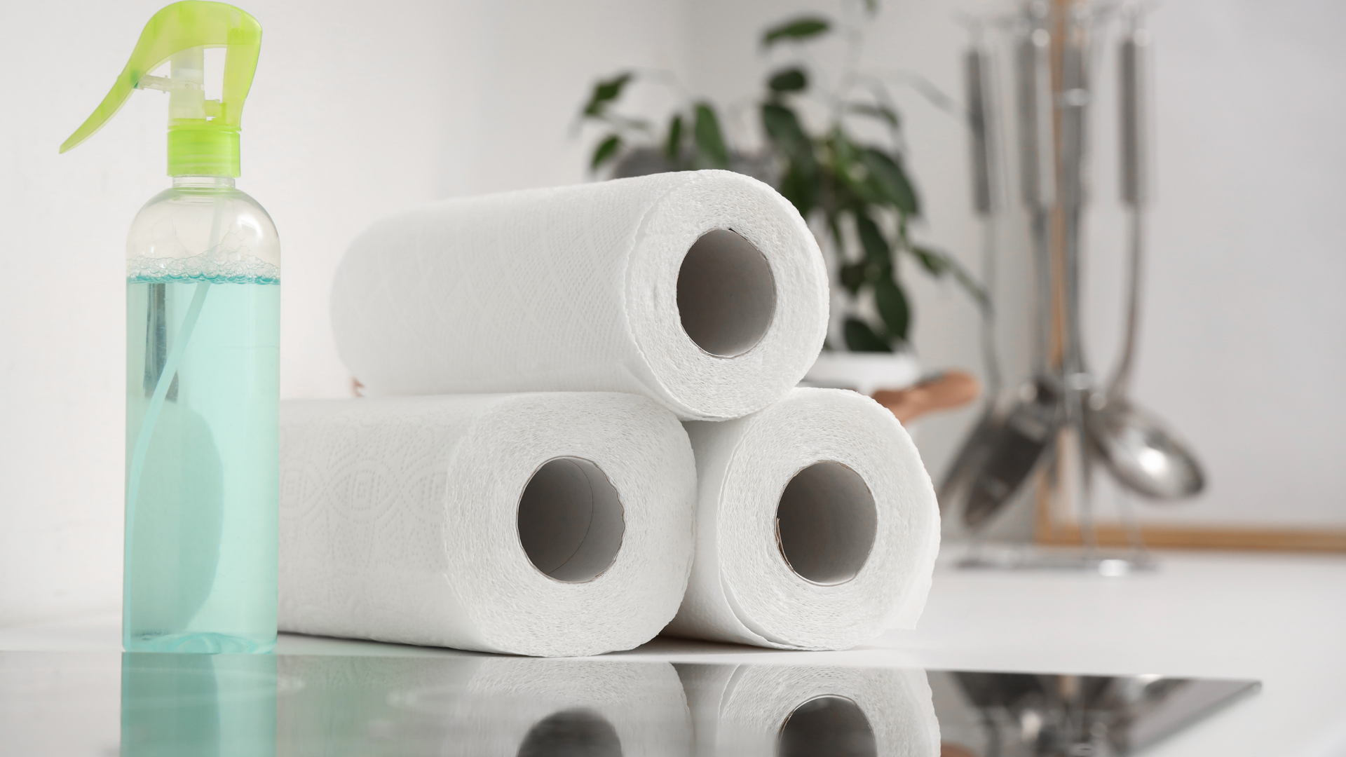 Woman spraying and wiping a mirror with a white cloth in a bathroom.