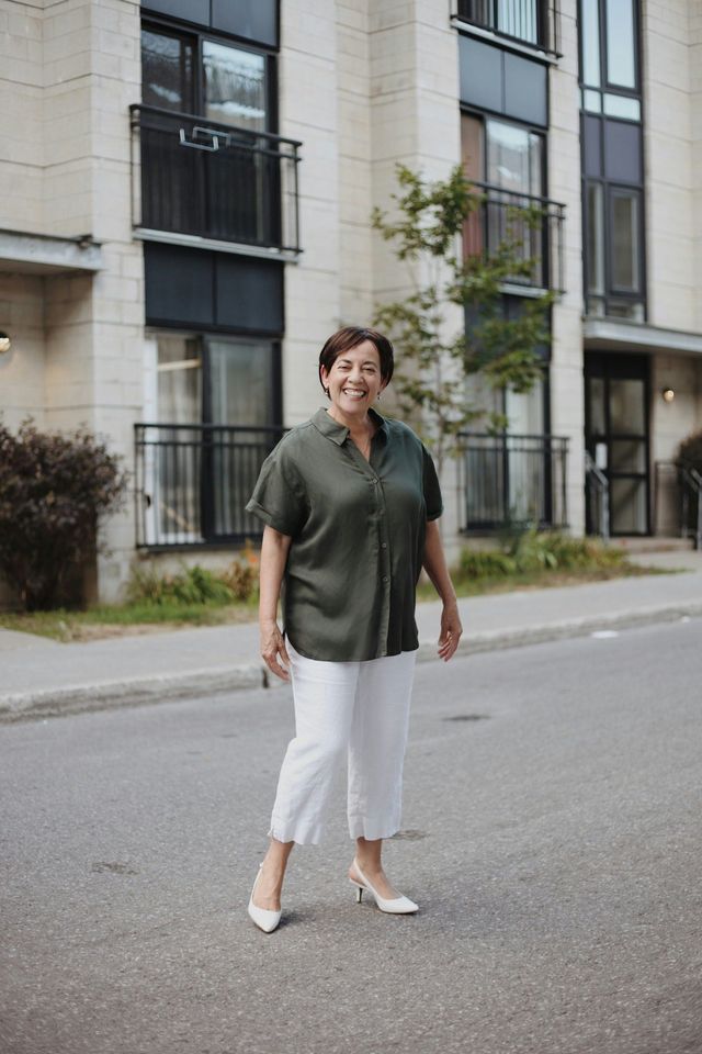 A woman is walking down the street in front of a building.