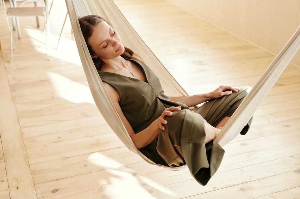 A woman in a green dress is sleeping in a hammock.