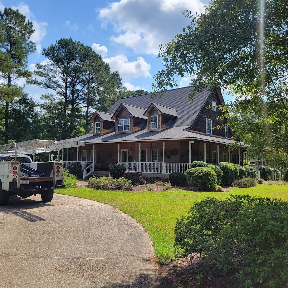 A truck is parked in front of a large house with a porch.