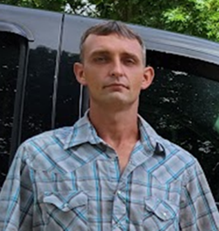 A man is standing in an empty room with boxes on the floor.