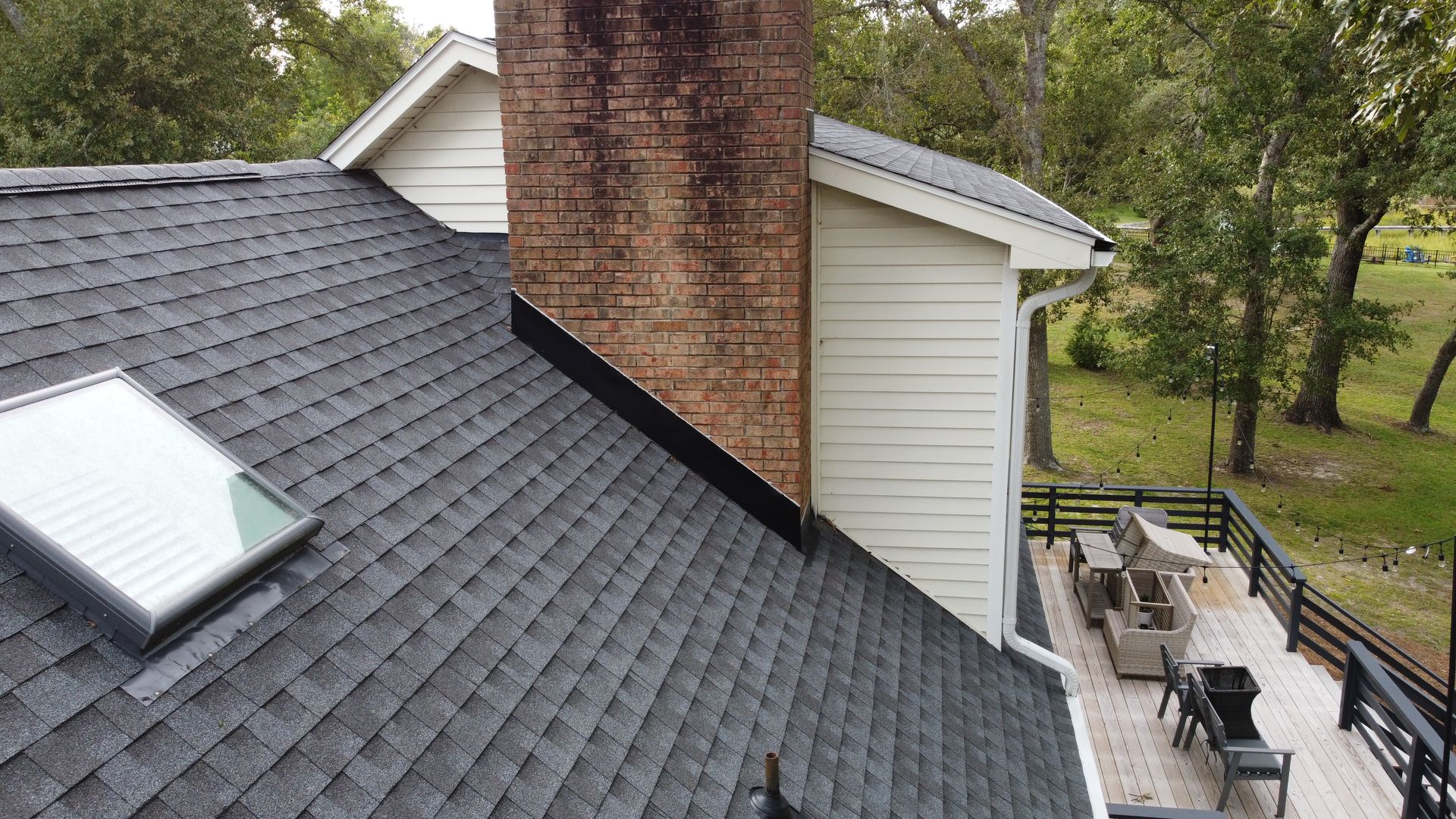 The roof of a house with a skylight and a chimney.