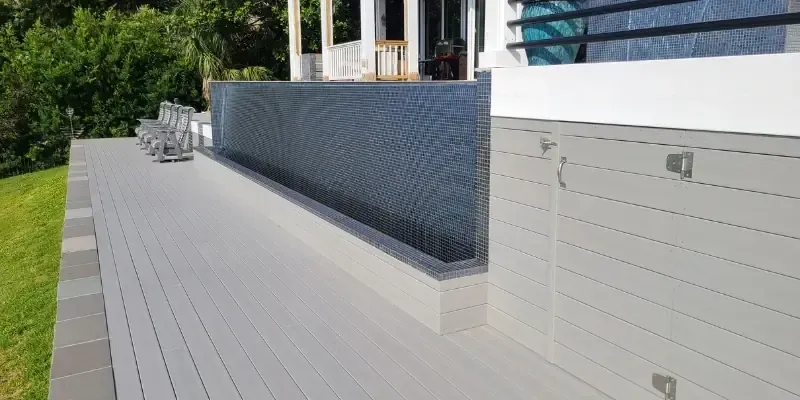 Completed composite pool deck in Porters Neck NC with gray decking beside tiled pool wall and clean finished edge
