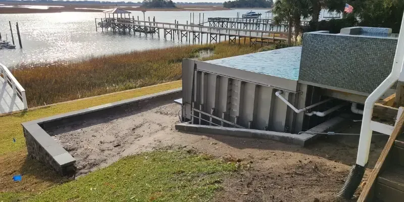 Pool deck site prep beside metal pool wall and retaining wall in Porters Neck NC