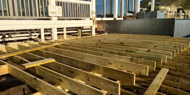 Pressure-treated deck framing in progress with joists set for composite decking installation