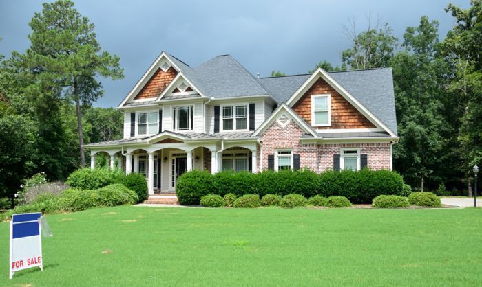A large house with a for sale sign in front of it. A large house with a for sale sign in front of it.