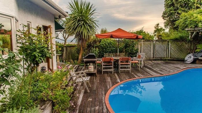 There is a large swimming pool in the backyard of a house.