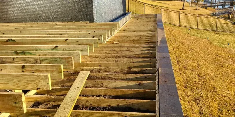 Deck framing layout with pressure-treated joists along retaining wall before decking install