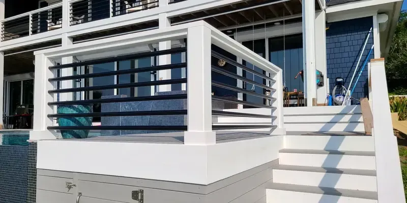 Cable railing detail with white posts and black horizontal rails on elevated deck stairs