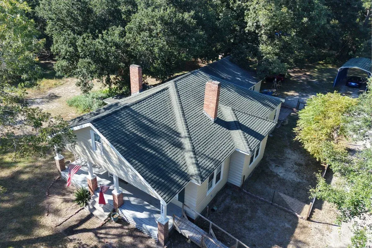 Old wore out roof in Sneads Ferry, NC with cracked shingles and leaky chimney flashings.