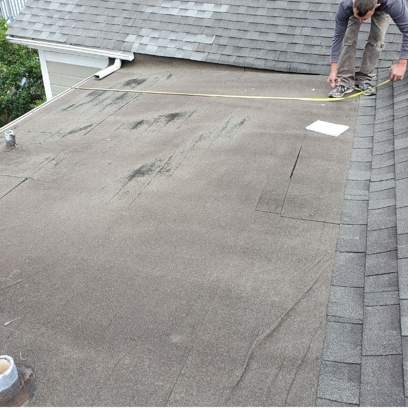 Roof inspection process photo showing technician evaluating shingles and flashing.