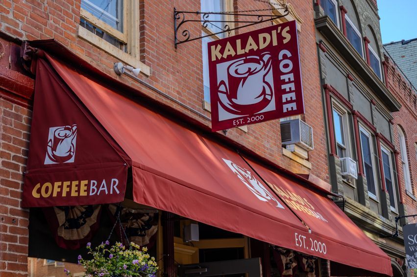 A coffee shop with a red awning and a sign that says kaladi 's coffee